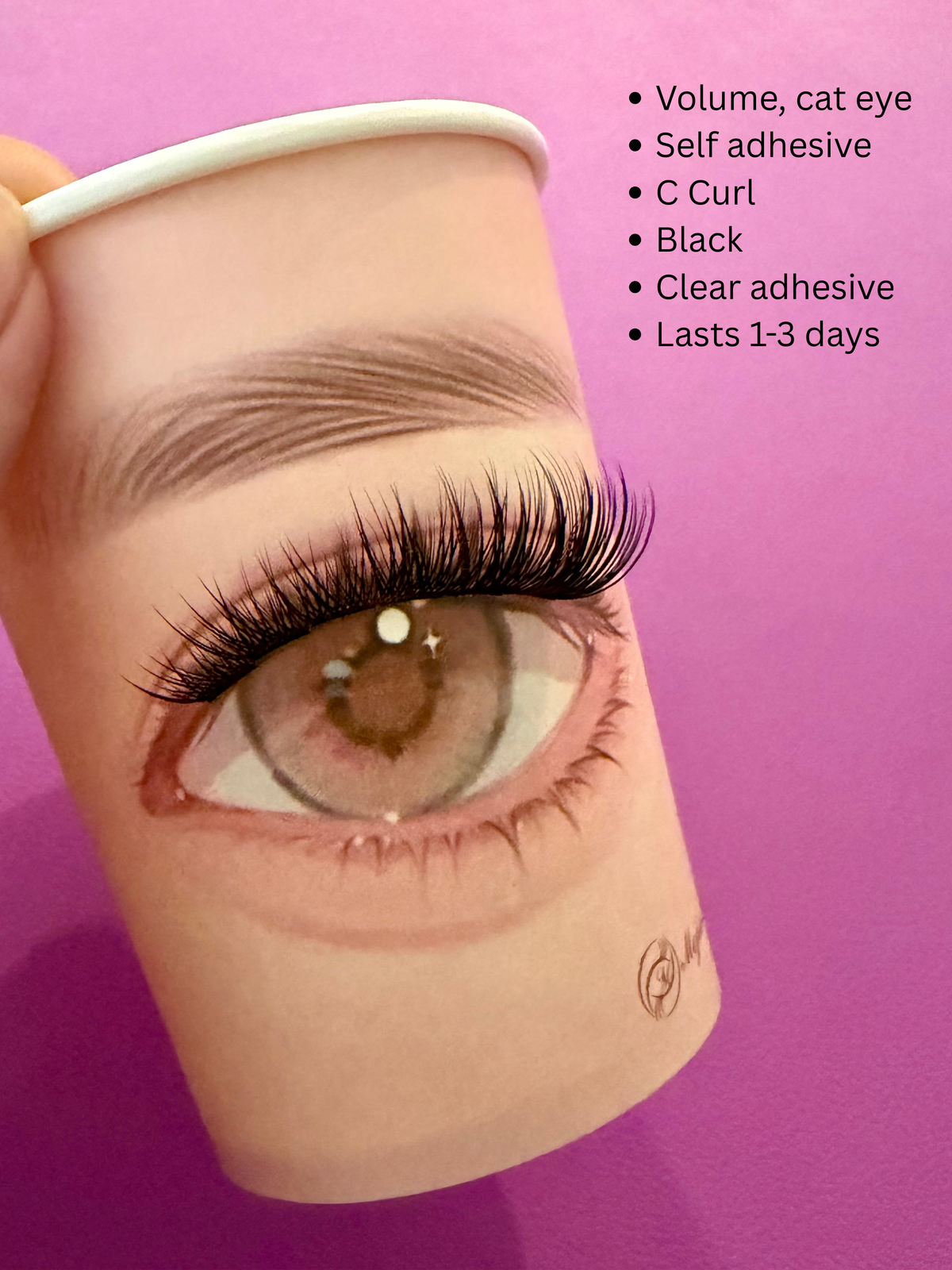 A close-up of a realistic false eyelash cluster applied to a printed eye on a cup, held against a bright pink background. Black text on the right lists features: volume, cat eye, self adhesive, C curl, black, clear adhesive, lasts 1-3 days.
